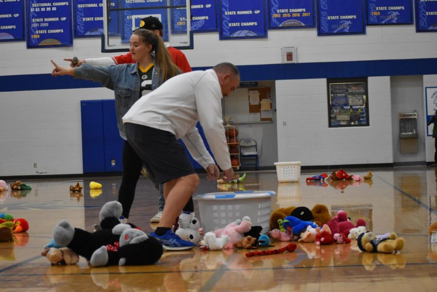 Athletic Director Shawn Groshek scurries to pick up stuffed animals during the teddy bear toss at halftime during the boys basketball game.