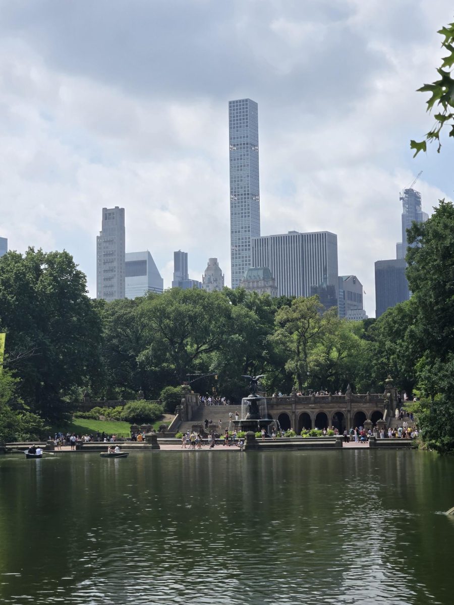 On July 30, we show a far away view of the Bethesda Terrace on the opposite side of the lake seen below it. New York City skyscrapers towering above the trees of Central Park are shown in the background.
